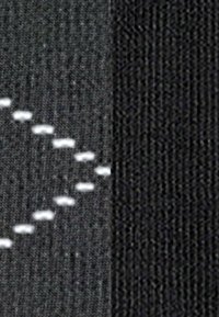 Macro di due trame di tessuto nero; il lato sinistro presenta cuciture bianche in una trama a punto tratteggiato, mentre il lato destro ha una finitura liscia.