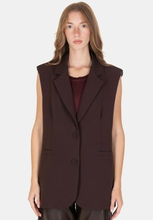 Blazer marrone senza maniche con rever incisato, due tasche frontali e chiusura con due bottoni. Tessuto liscio con vestibilità sartoriale.