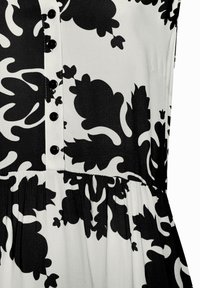 Schwarz-weißes Kleid mit Blumenmuster, das über eine Knopfleiste, eine geraffte Taille und eine glatte Stoffoberfläche verfügt.