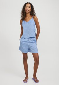 Blå mönstrad topp och shorts-set med avslappnad passform, tillverkat av lättviktsmaterial. Har tunna axelremmar och sidofickor.