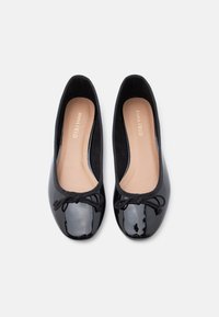 Μαύρα μπαλαρίνα παπούτσια από δερμάτινο πατεντέ με στρογγυλεμένη μύτη, ελαστικό περίγραμμα και διακοσμητικό φιόγκο μπροστά. Λείο φινίρισμα και μαλακό πάτο με επένδυση.