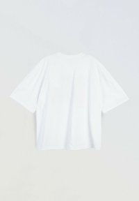 Prosta, biała, oversize koszulka z krótkim rękawem wyłożona na płasko, pokazująca tył z okrągłym dekoltem na białym tle.