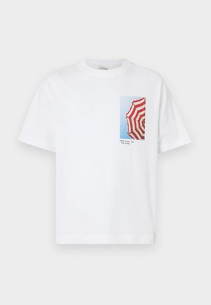 Biała koszulka z nadrukiem zdjęcia parasola w czerwono-białe paski na tle niebieskiego nieba, z napisem "GOOD TIMES AND TAN LINES" poniżej.