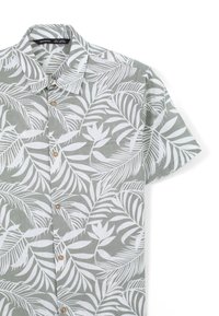 Camicia a maniche corte con bottoni in tessuto grigio chiaro con motivo di foglie tropicali bianche; presenta un colletto classico e bottoni in legno.