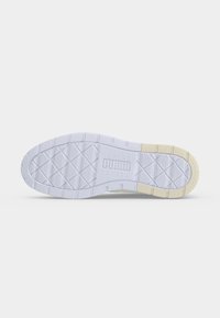 Semelle blanche de basket Puma avec motif en diamant et partie beige près des orteils sur un fond clair.