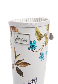 Maceta blanca con diseños coloridos de flores y mariposas. Incluye una placa con un logotipo plateado y un borde texturizado con un mango resistente.