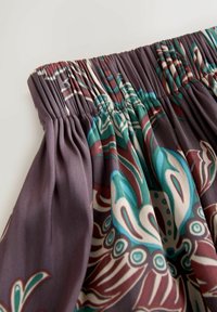 Tkaninový top s elastickým naznačením. Obsahuje květinový vzor v barvách tyrkysové, vínové a krémové na tmavě fialovém pozadí. Hladká textura.