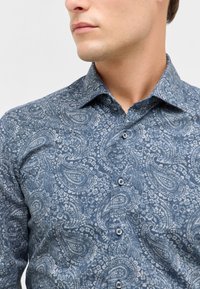 Camicia in tessuto morbido con motivo paisley blu, dotata di colletto button-down, bottoni frontali e dettagli floreali intricati.