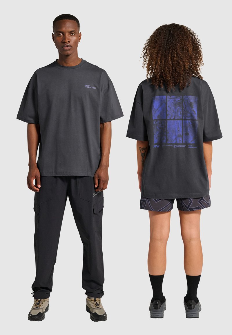 Czarny szary oversize t-shirt z logotypem na piersi, niebieski wzór graficzny z tyłu. W połączeniu z czarnymi spodniami cargo i wzorzystymi szortami.