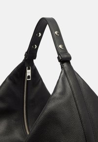 Czarna skórzana torebka o trójkątnym kształcie, z teksturowaną powierzchnią, srebrnym zamkiem błyskawicznym oraz mocnym paskiem z metalowymi zapięciami.