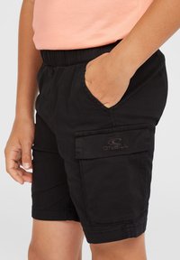 Svarta cargo-shorts med elastisk midja, sidofickor och en ficka med en logotyp. Lättviktsmaterial och slät yta.
