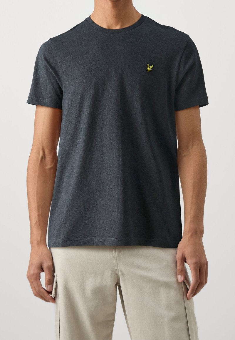 Camiseta de manga corta de color gris oscuro, hecha de algodón, con cuello redondo y un pequeño logo verde bordado en el lado izquierdo del pecho.