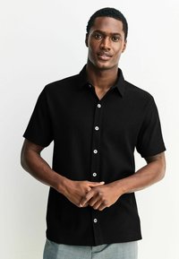 Sort kortærmet skjorte med ribbet tekstur, skræddersyet design og hvide knapper. Glat stof og klassisk krave detaljer.