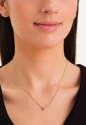 Gouden ketting met een kleine, Y-vormige hanger versierd met heldere edelstenen. Eenvoudig ontwerp met een glad, gepolijst oppervlak.