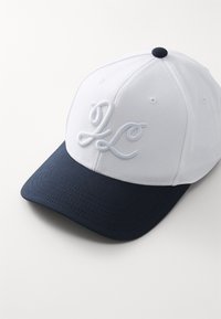 Czapka baseballowa z białą tkaniną korony i granatowym daszkiem. Posiada haftowane inicjały na przodzie w kolorze białym oraz teksturowany daszek.