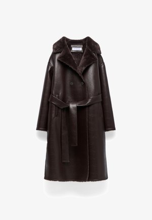 Manteau marron en cuir double boutonnage avec un col en fausse fourrure, taille ceinturée et manches longues. Présente une texture et une coupe droite.
