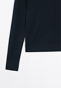 Dark navy knit sweater featuring a soft texture, long sleeves, and a ribbed hem. Simple design with no visible patterns or hardware.