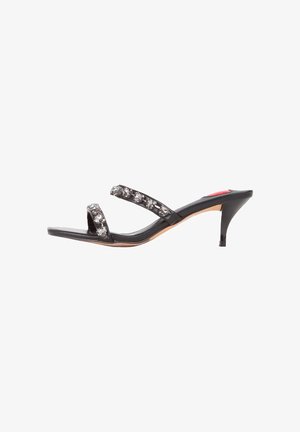 Black open-toe heels with two thin straps adorned with clear rhinestones, featuring a tapered 5 cm heel and a smooth leather finish.