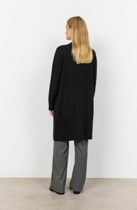 Black knitted long cardigan with ribbed texture, featuring long sleeves and a straight cut, paired with gray striped wide-leg trousers.