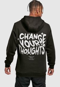Black hoodie featuring large white text that reads "CHANGE YOUR THOUGHTS" on the back, with ribbed cuffs and hem.