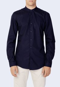 Camicia blu navy a maniche lunghe con colletto alla cinese. Realizzata in tessuto morbido, presenta bottoni frontali e una vestibilità su misura.