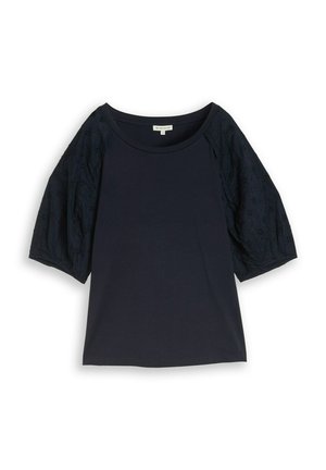 Granatowa bluzka z krótkim rękawem o okrągłym dekolcie oraz bufkami z koronki zdobionymi kwiatowymi wzorami wycięć.