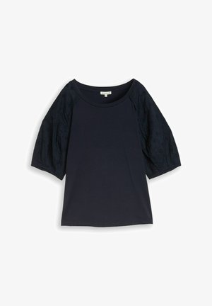 Granatowa bluzka z krótkim rękawem o okrągłym dekolcie oraz bufkami z koronki zdobionymi kwiatowymi wzorami wycięć.