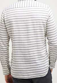 Camicia a maniche lunghe in tessuto leggero con righe orizzontali bianche e grigie. Caratterizzata da un colletto con bottoni e polsini con chiusura a bottone.