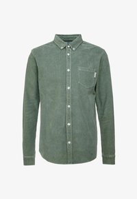 Chemise verte en velours côtelé à manches longues avec col et poche poitrine à gauche, présentée sur un fond uni.