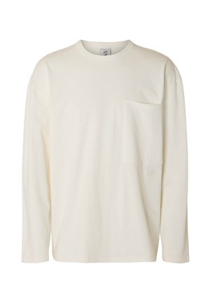 Pika varrukaga kreemjas särk, valmistatud pehmest kangast, millel on rinnatasku ja mugav lõige. Lihtne disain ilma nähtavate mustrite või lisanditeta.