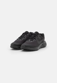 Scarpe da ginnastica nere con tomaia in mesh testurizzato, suola spessa e imbottita, e design con lacci, caratterizzate da un grande logo swoosh sul lato.