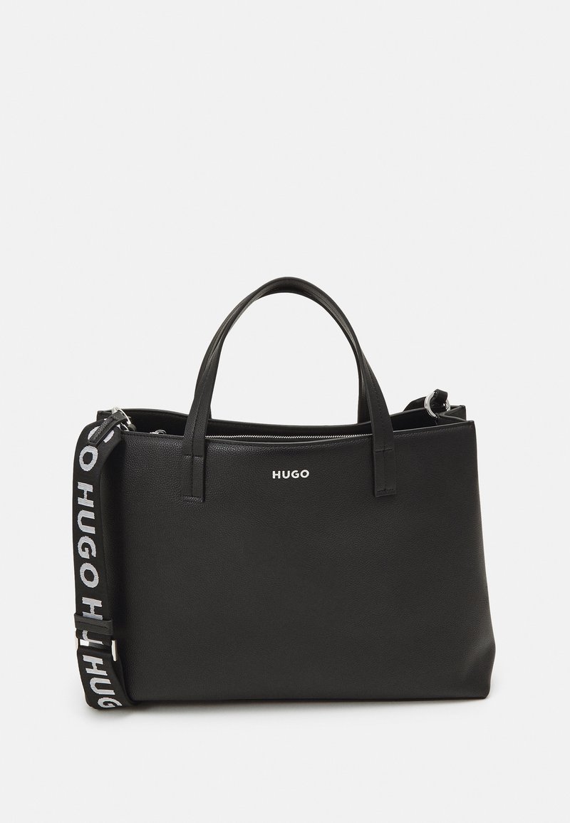 Sac à main rectangulaire noir avec deux poignées supérieures, une bandoulière détachable avec le texte "HUGO", et un logo imprimé en blanc à l'avant.