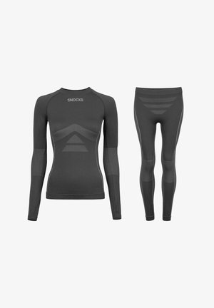 Czarna sportowa bluzka z długim rękawem oraz legginsy z teksturowanymi panelami, dopasowanym krojem i odblaskowymi akcentami. Logo marki na bluzce.