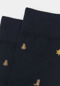 Marineblå sokker med ribbet tekstur, der har mønstre af brune pengeposer og støvler, samt en gul sheriffstjerne som detalje.