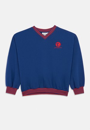 Μπλε φούτερ με μακριά μανίκια, κόκκινες ρίγες στο V-λαιμό, στις μανσέτες και στο τελείωμα, με κόκκινο γραφικό της υδρογείου και κείμενο στο αριστερό στήθος.