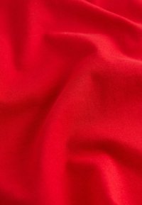 Red cotton fabric with a smooth, slightly shiny texture, displaying soft folds and subtle variations in color.