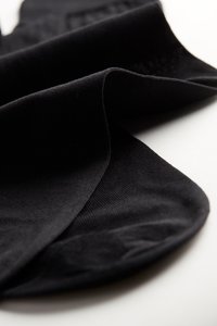 Černá ponožka vyrobená z hladkého, elastického materiálu, s kulatou špičkou a žebrovaným lemem pro lepší přilnavost. Položená na plocho, zdůrazňující texturu látky.