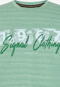 Camiseta verde de manga corta con un tejido texturizado, con un gran texto en blanco y verde que dice "1967 Signal Clothing", adornada con sutiles patrones de hojas.