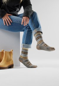 Calze di lana con un motivo multicolore che presenta accenti grigi, gialli e marroni. Parte superiore a costine, tallone e punta rinforzati. Vestibilità casual con jeans.