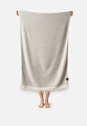 Coperta in tessuto intrecciato con un motivo grigio chiaro, bordi frangiati e superficie testurizzata. Il materiale è morbido e leggero.