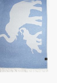 Light blue blanket featuring white silhouettes of an elephant and a calf, with fringed edges and soft texture. Tag at bottom left corner.