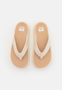 Beige flip-flops with a textured footbed, a Y-shaped strap, and a durable sole. Brand logo prominently displayed on the footbed.