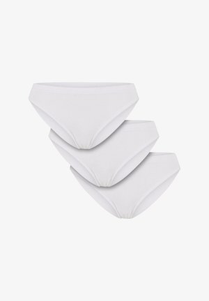 Brassière blanche à côtes avec dentelle et culotte blanche assortie. Le modèle se tient de manière confiante, portant des chaussettes blanches, sur un fond uni.