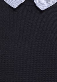 Morski sweter o teksturowanym wzorze dzianiny, z kontrastującym kołnierzem w niebiesko-białe paski.