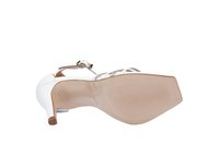 Zapato de tacón alto blanco con tiras delgadas en el tobillo, parte superior transparente y punta afilada. Suela de goma texturizada, altura de tacón modesta.