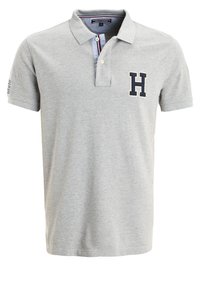 Polo gris clair à manches courtes, avec col, patte de boutonnage et lettre H en contour foncé sur la poitrine gauche.