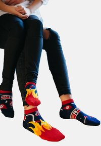 Calze alla caviglia colorate con tessuto blu navy e motivi di fiamme e automobili; accenti rossi sul polsino e elementi di design unici.
