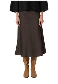 Brązowa satynowa spódnica midi z rozkloszowanym dołem, zestawiona z beżowymi zamszowymi kozakami do kolan, wystylizowana z czarnym, teksturowanym, oversize'owym swetrem.