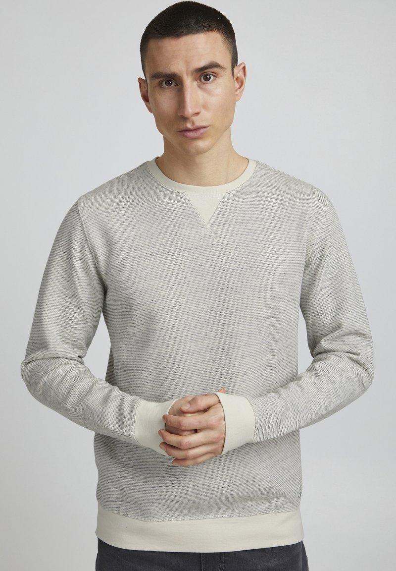 Lys grå sweatshirt med teksturert stoff, ribbede mansjetter og nederkant, rund hals og V-søm detalj på kragen. Nyttig design.