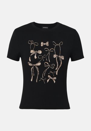 Camiseta negra de manga corta con un patrón abstracto de lazos en marrón claro y dorado en el frontal. Tela de algodón suave, cuello redondo.